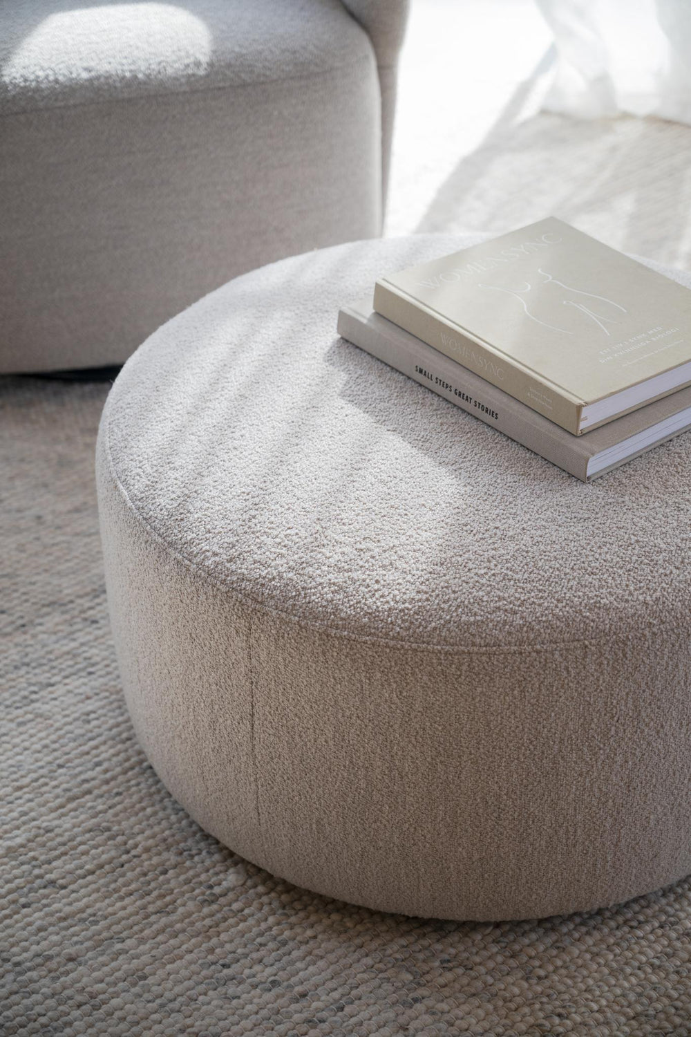 Rund sittpuff i beige teddy-tyg med låg profil och diskreta ben
