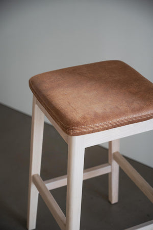 Pall med brunt lädersits och vitlaserade trä ben, kvadratisk sits med synliga sömmar