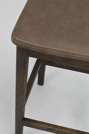 Barstol med brunt konstläder och mörkbruna träben med synlig sömdetalj
