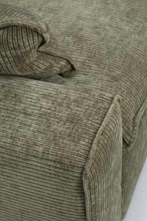 Grön manchester soffa med ribbad struktur och mjuka dynor i närbild
