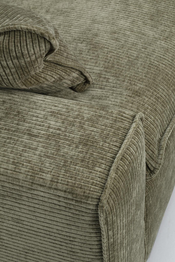 Grön manchester soffa med ribbad struktur och mjuka dynor i närbild