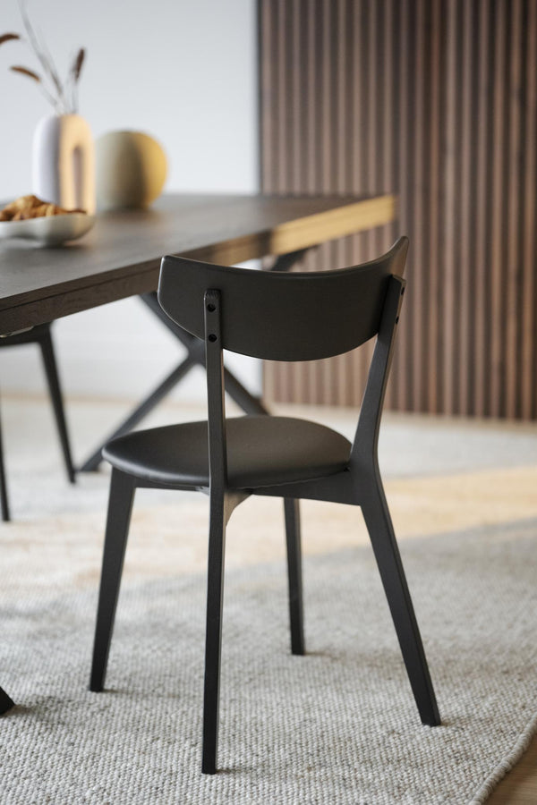 Svart trästol vid matbord i modern skandinavisk matsal med ribbad vägg i bakgrunden