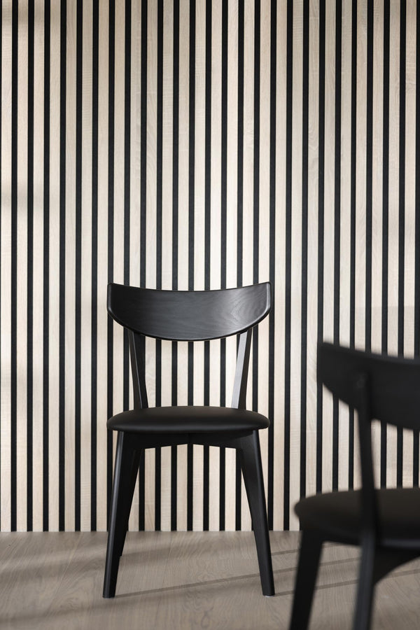 Svart matstol med trärygg och stoppad sits mot randig vägg i modernt skandinaviskt designkök