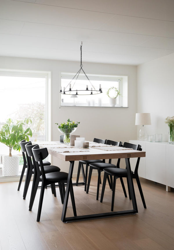 Minimalistisk matplats med vitt marmorbord, svarta stolar och modern taklampa i ljust skandinaviskt kök