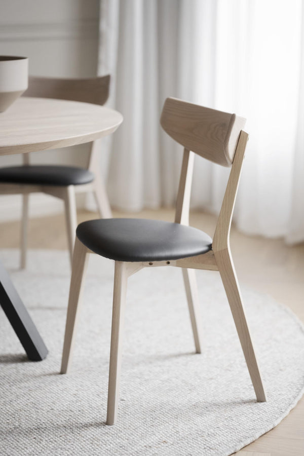 Ljus trästol med grå stoppad sits vid runt matbord i skandinavisk stil