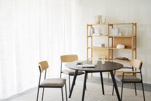 Matbord i svart med fyra stolar och bokhylla i ljust trä i modern skandinavisk matsal