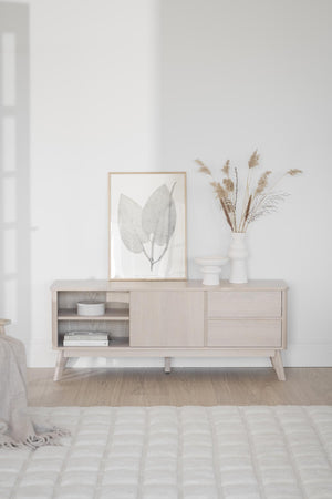 Ljust sideboard i trä med skjutdörr och lådor, dekorerat med ram och torkade blommor i skandinavisk stil