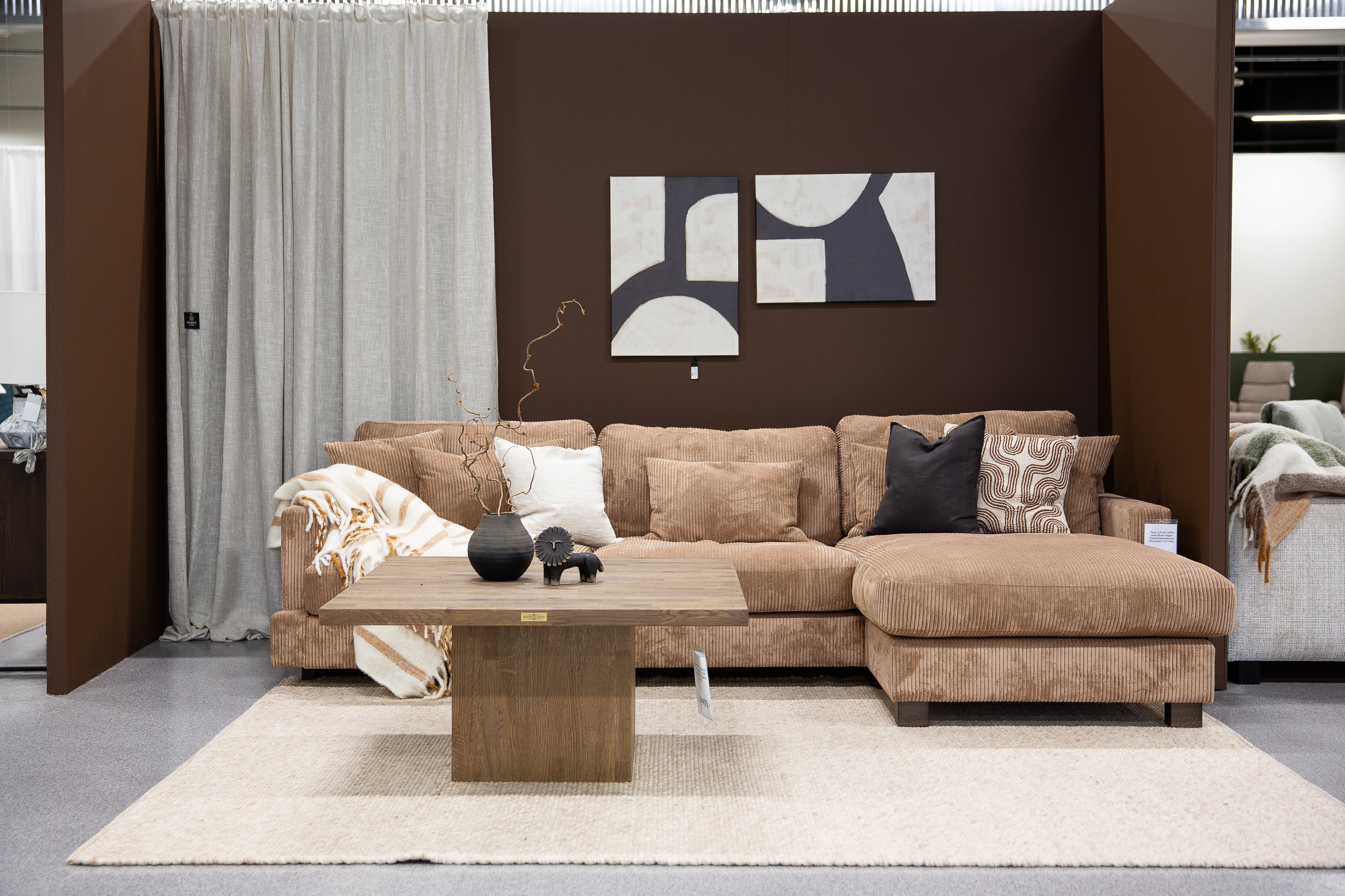 Beige corduroy hörnsoffa med schäslong i modernt vardagsrum med bruna väggar och abstrakt konst