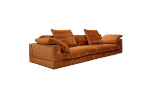 Stor orange soffa i sammet med lösa dynor och låg profil, vinklad vy från sidan