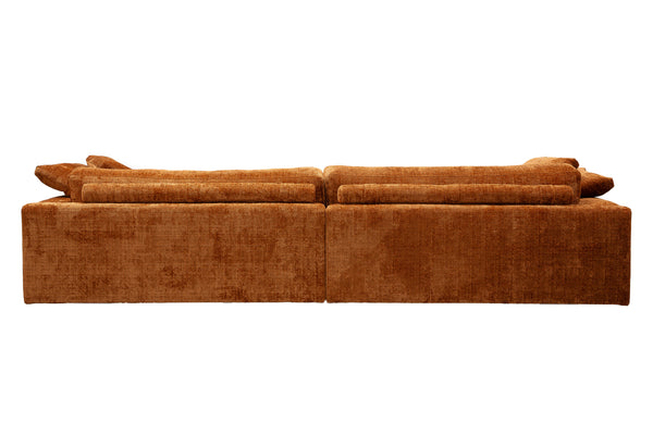 Orange sammetssoffa med avtagbara kuddar sedd bakifrån mot vit bakgrund