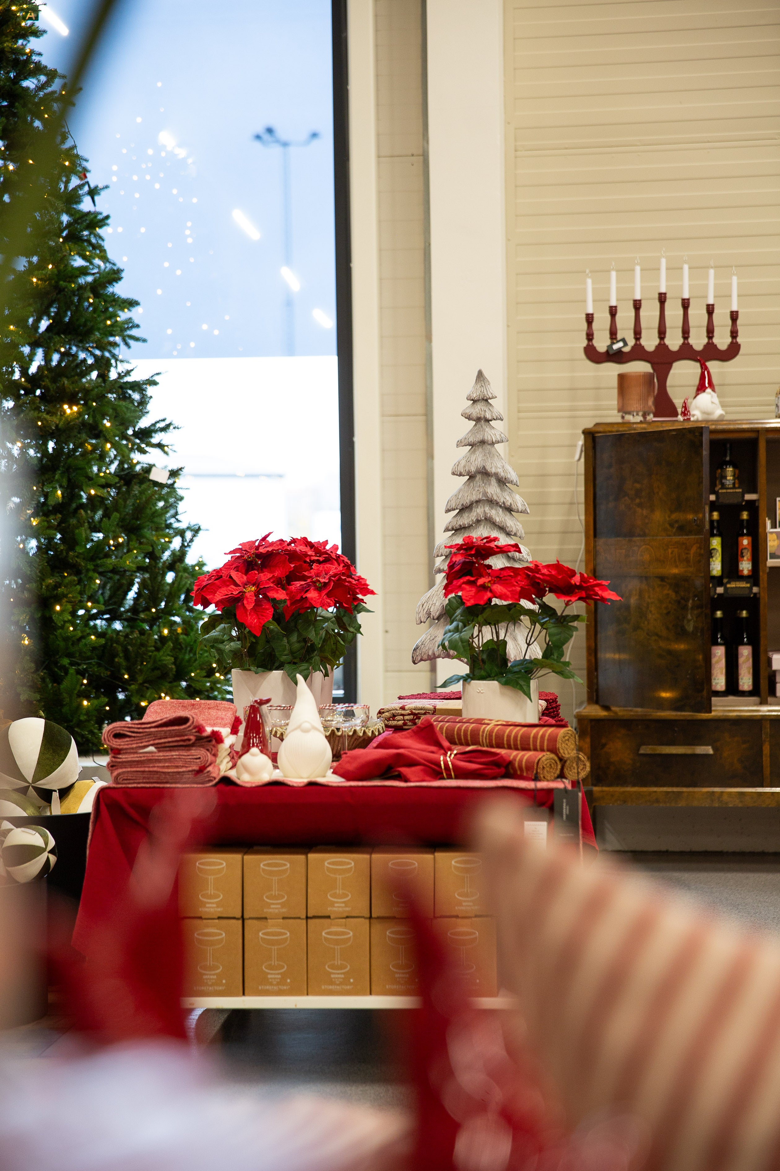 Juldekoration med röda julstjärnor, granris, ljusstake och textilier i festligt arrangerad inredning