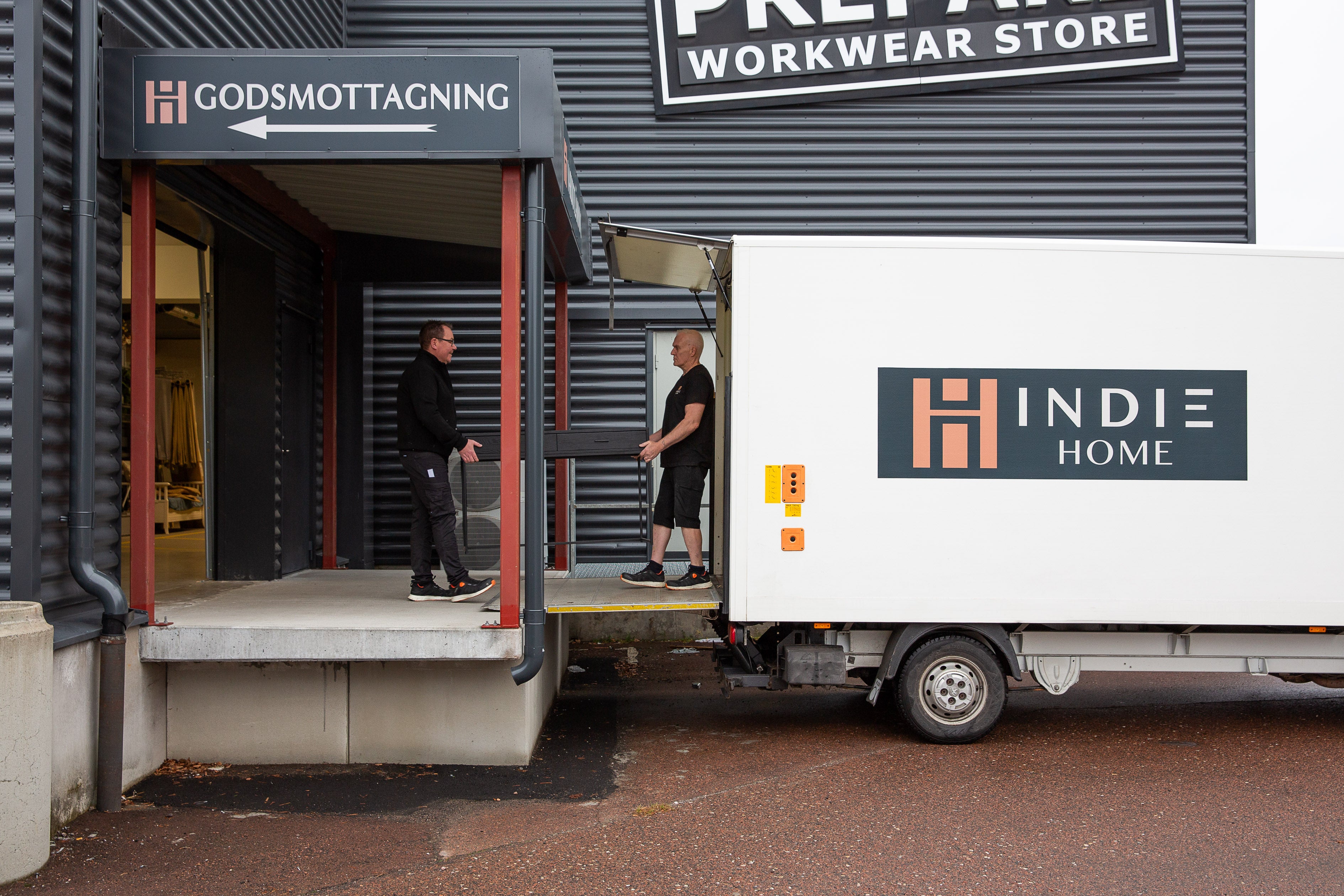 Lastbil från Indie Home vid lastkaj under godsmottagning på lager med two personer