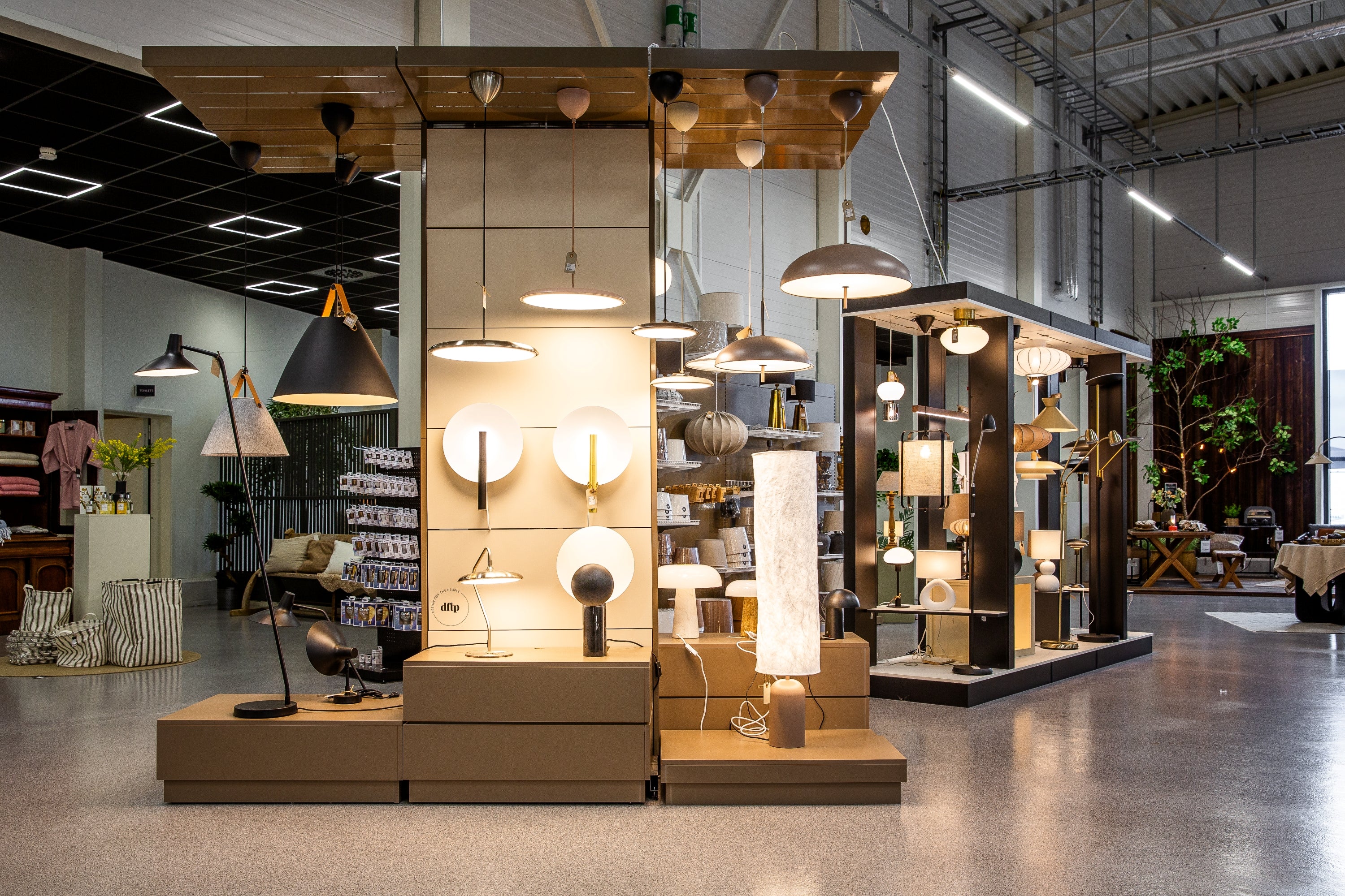 Ljusutställning med moderna taklampar, golvlamor och bordslampor i showroom med industriell inredning