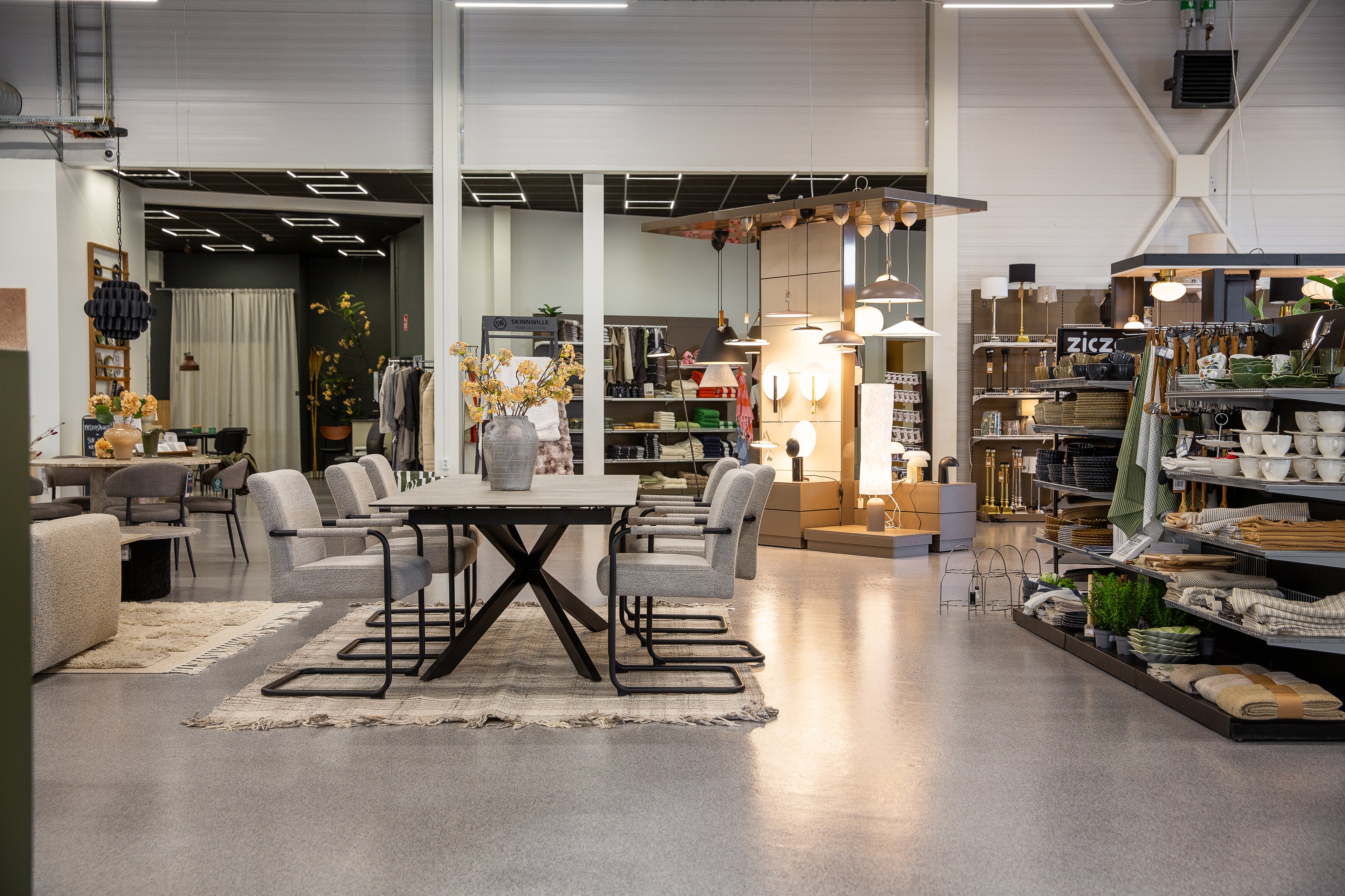 Modern matplats med svart bord, grå stolar och inredningsdetaljer i showroom med betonggolv